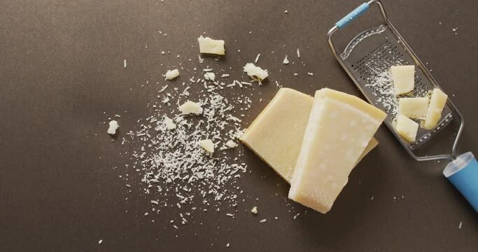 Video of block of parmesan cheese and cheese grater cheese on wooden table