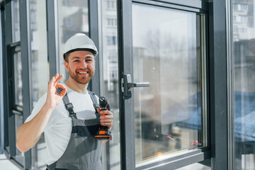 Using the drill. Repairman is working indoors in the modern room