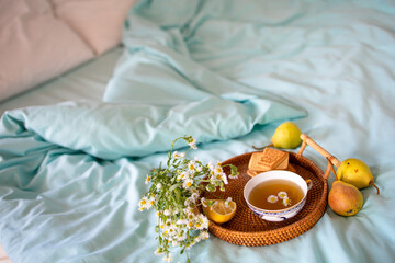 a cup of hot tea with chamomile on a tray in bed. Blue sheets with breakfast in bed.