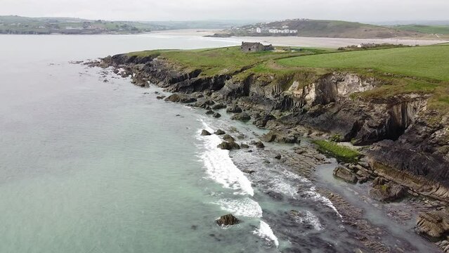 Green fields on a rocky seashore in Ireland. The waters of the Celtic Sea hit the rocks. Seashore, landscape.