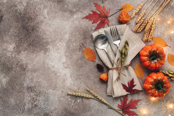Fototapeta Autumn table setting place with cutlery and pumpkins, brown grunge background. Thanksgiving and halloween concept. Top view, flat lay. obraz