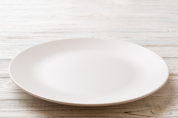 Perspective view of empty light plate on wooden background. Empty space for your design