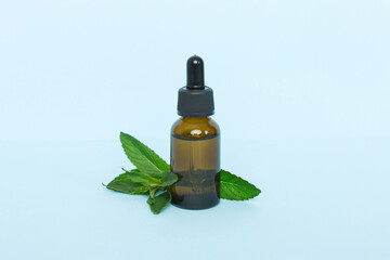 Natural Mint Essential Oil in a Glass Bottle. organic cosmetics with herbal extracts of mint on colored background