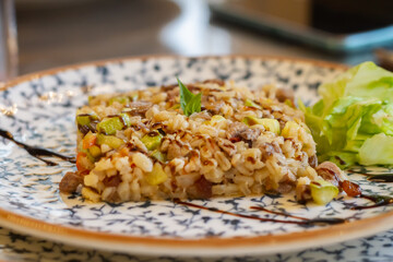 Warm pearl barley salad with meat and zucchini decorated with green lettuce leaves