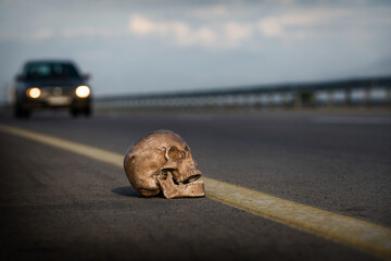 Dummy human skull on a freeway and a car moving at high speed