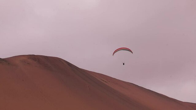 Parachute, parasailing in Peruvian dunes, Paracas National reserve, twisting..