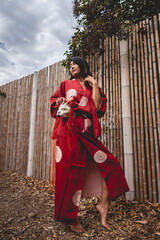Portrait of sexy and young japanese girl with beautiful old traditional red kimono and handmade cat...