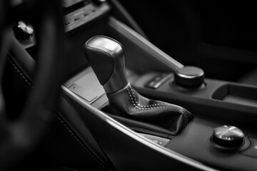 Black and white chrome gear shift stick with high tech button control panel inside a modern luxury...