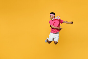 Young happy fun expressive man 20s he wear pink t-shirt near hotel pool jump high play guitar look aside on workspace area mock up isolated on plain yellow background Summer vacation sea rest concept