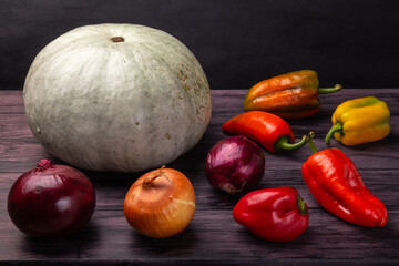 pumpkin, onions and bell peppers on a dark background  
