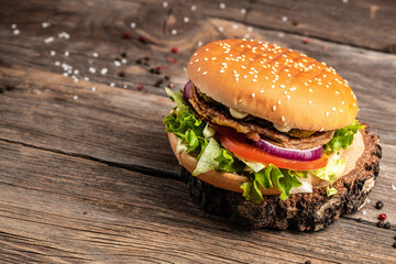 Homemade burger with grilled meat, vegetables, sauce on rustic wooden background. fast food and junk food concept
