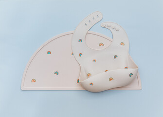 Silicone bib on light blue background, flat lay. Serving baby food, first feeding concept. Flat lay, copy space, top view