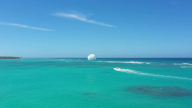 Parasailing tourists above caribbean sea. Tropical vacation. Dominican Republic. Aerial drone view