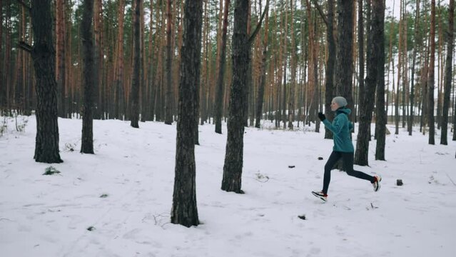 woman sportswear sprinting fast exercising cardio workout in winter focused female running in forest athlete training for marathon competition