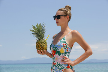 Happy young woman drinking fresh pineapple cocktail at the beach. Exotic summer vacation.