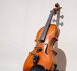 Fototapeta na wymiar Elegant 150 years old violin reclining in the light with shadow on the wall 