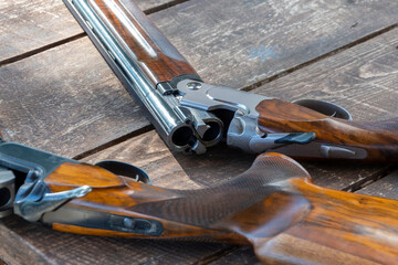 Sporting double-barreled shotguns lie on a wooden table, selective focus. bench target shooting.