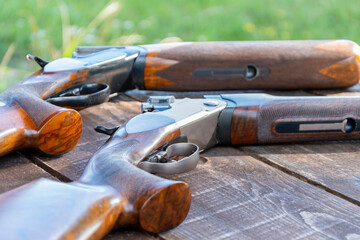 Sporting double-barreled shotguns lie on a wooden table, selective focus. bench target shooting. - obrazy, fototapety, plakaty