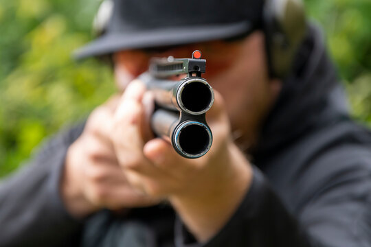 A male shooter aims a sporting double-barreled hunting rifle, target shooting, selective focus.