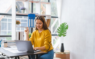 Smiling young asian student studying on online courses improving professional knowledge or...