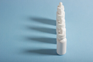 A set of white cosmetic bottles with a dropper lined up with hard shadows. The concept of face and body care at home and in a beauty salon