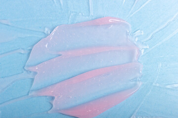 Abstract patterns of transparent moisturizing facial gel. The texture of the cosmetic product is smeared on a blue background.