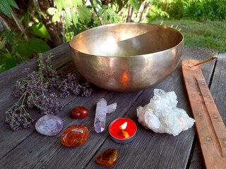 Tibetan singing bowl with crystals, candle, dried flowers, incense - altar on a wooden table....
