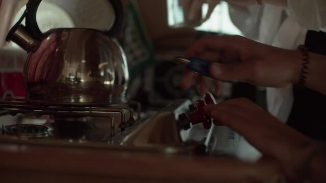 A young couple is boiling water in the kettle inside a camper 