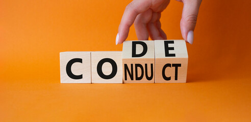 Code of conduct symbol. Businessman hand Turnes cubes and changes word Conduct to Code. Beautiful orange background. Business and Code of conduct concept. Copy space