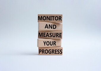Monitor and Measure your Progress symbol. Wooden blocks with words Monitor and Measure your Progress. Beautiful white background. Business and Monitor and Measure your Progress concept. Copy space