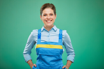 woman worker in overalls with hands in pockets. isolated on green background.
