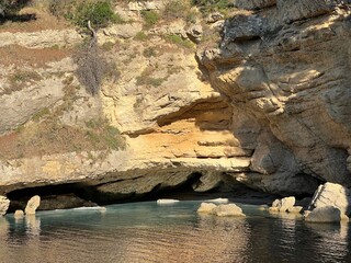 Hidden cave in the sea. Beautiful Beach with clear turquoise waters and steep cliffs.