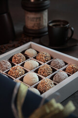 Handmade round shaped candies. Candy in a box. The concept of the holiday . A sweet gift.. Selective focus. A cup of coffee and a coffee grinder are out of focus.