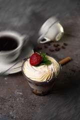 Classic tiramisu dessert with strawberries in a cup and coffee on the table