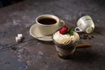 on the table dessert tiramisu with strawberries and a cup of coffee