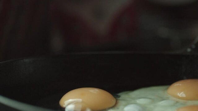 Close-up of eggs being cracked into the pan