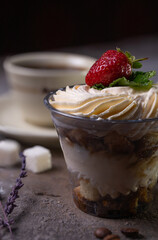 Classic tiramisu dessert with strawberries in a cup and coffee on the table