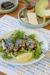 Fresh and crispy fried anchovies served with lemon slices and green leaves salad. Ideal summer bite.