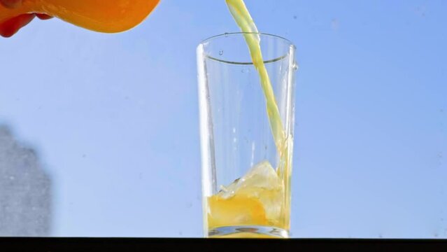 Pouring orange drink into the glass slowmotion