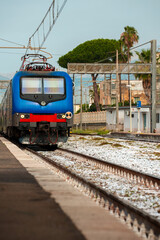 Naklejka premium Train arrives at regular rural train station in Italy.