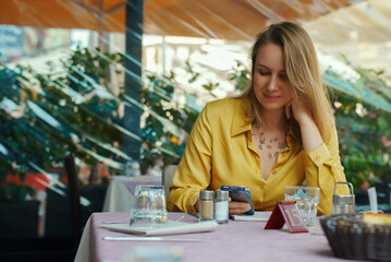 Woman is looking at menu via qr code in restaurant.