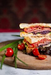juicy crispy sandwich with ham and vegetables close-up on the board
