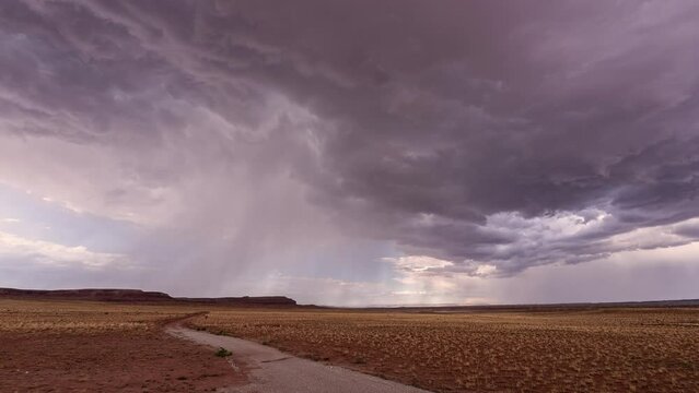 Dirt road leading to storm moving through the Utah desert as it rains during monsoon season.