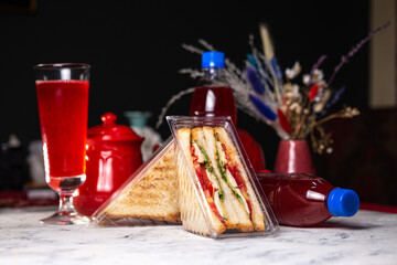 sandwich with filling in a plastic package and a drink in a bottle