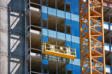 Workers team installing glass windows on building at height. Installation of double-glazed windows...