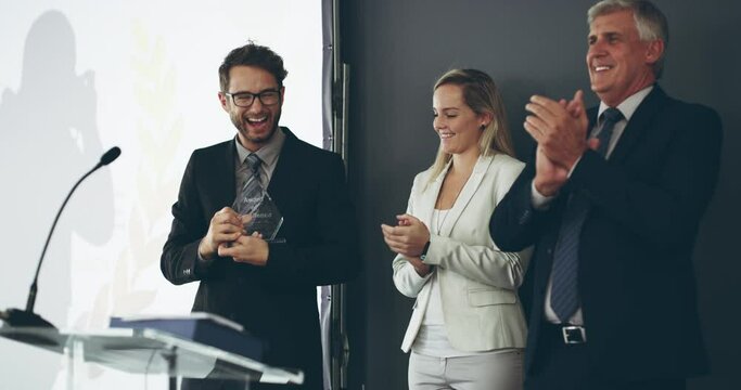 Excited business man celebrating success, winning a prize at an award ceremony while his male colleague and female coworker are clapping. Young male cheering his win or victory at a conference