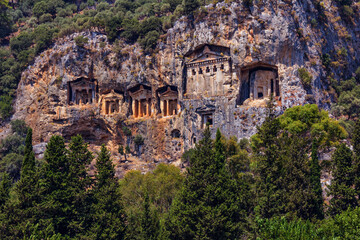 Fototapeta premium Famous rock-cut Lycian grave tombs of kings in carved caves in the cliffs of ancient Caunos (Kaunos) town, a UNESCO world heritage site at Dalyan, Mugla, Turkey.