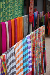 Traditional Loas weaving village with textiles hung for sale on bamboo hangers.