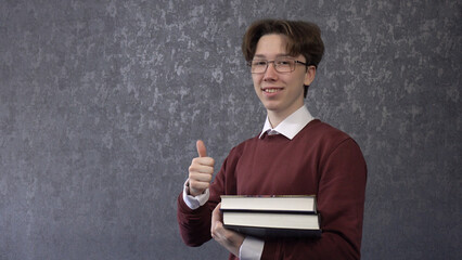 A teenage student with a book in his hands. On a gray background.