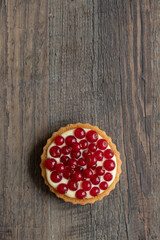 rote Johannisbeeren und Pudding in Törtchen auf Tisch aus Holz